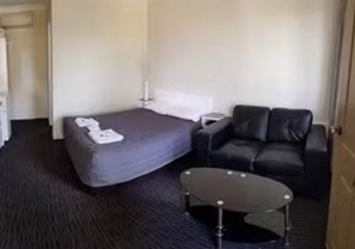 Blayney Goldfields Motor Inn room featuring a bed, a seating area, and a dark carpet.