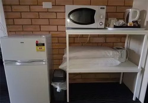 Blayney Goldfields Motor Inn room with two-door mini-refrigerator, white microwave oven and a tray with a white electric kettle and various coffee/tea supplies.